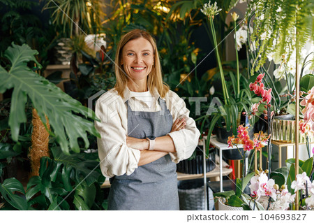 Smiling woman florist small business owner standing with crossed arms in own floral store Smiling woman florist small business owner standing with crossed arms in own floral store 104693827