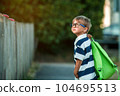 Back to school. A boy from an elementary school with a backpack on the street. The concept of the day of knowledge, The beginning of school. Smart little child in glasses 104695513