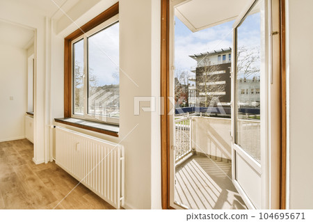 an empty room with wood flooring and large windows looking out onto the street in front of the apartment building an empty room with wood flooring and large windows looking out onto the street in front of the apartment building 104695671