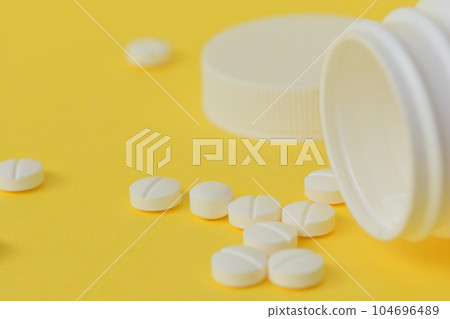 Medicine spilled from white bottle on yellow paper Medicine spilled from white bottle on yellow paper 104696489