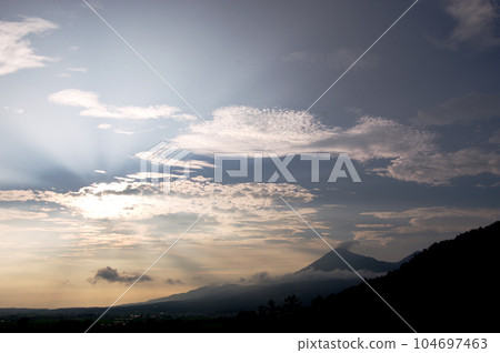 放射狀的夕陽從雲層中射出，與萬代山的剪影相映襯，在藍天的襯托下顯得格外美麗。 104697463