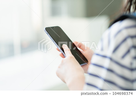 Female college student operating a smartphone Female college student operating a smartphone 104698374