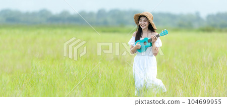 Lifestyle asian women white dress holding a guitar on a cloudy sunrise sky in the meadow flower, Lifestyle asian women white dress holding a guitar on a cloudy sunrise sky in the meadow flower, 104699955