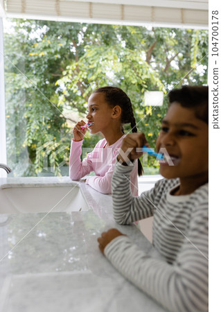 Biracial brother and sister in pyjamas brushing teeth together in the morning in bathroom Biracial brother and sister in pyjamas brushing teeth together in the morning in bathroom 104700178