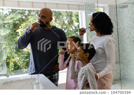 Biracial parents, son and daughter brushing teeth together in bathroom in the morning 104700394