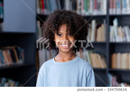 African american schoolboy wearing blue long sleeve t shirt with copyspace over library 104700616