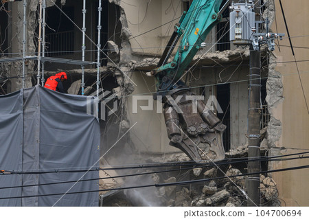 Aged public housing to be demolished Work scene of dismantling with a large heavy machine Aged public housing to be demolished Work scene of dismantling with a large heavy machine 104700694