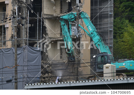 Aged public housing to be demolished Work scene of dismantling with a large heavy machine Aged public housing to be demolished Work scene of dismantling with a large heavy machine 104700695