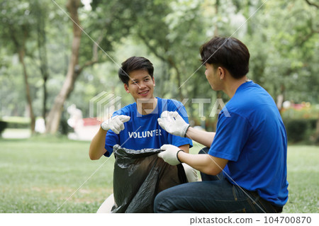 Young Asian Volunteers with garbage bags cleaning park area. Ecology, Charitable organization concept Young Asian Volunteers with garbage bags cleaning park area. Ecology, Charitable organization concept 104700870