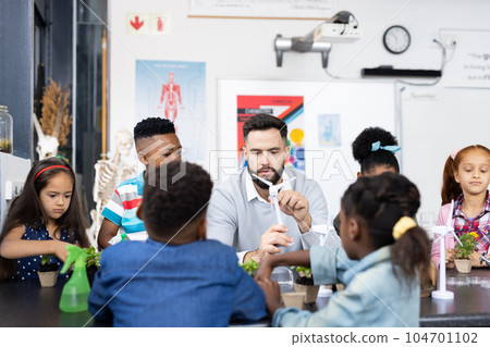 Diverse elementary schoolchildren and male teacher studying wind turbine together in school class Diverse elementary schoolchildren and male teacher studying wind turbine together in school class 104701102