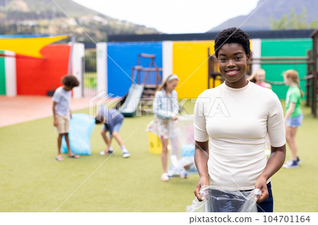 Portrait of smiling african american female teacher collecting recycling in schoolyard, copy space Portrait of smiling african american female teacher collecting recycling in schoolyard, copy space 104701164