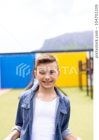 Vertical portrait of smiling caucasian schoolboy in schoolyard, with copy space 104701209