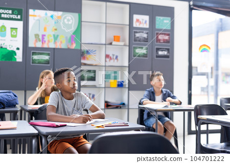 African american schoolboy working at desk in class with diverse pupils, copy space African american schoolboy working at desk in class with diverse pupils, copy space 104701222