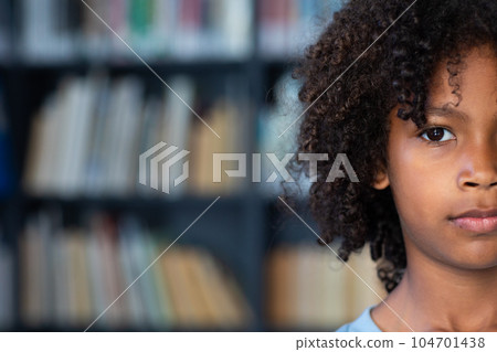 Half face portrait of african american schoolboy with afro hair in library with copy space Half face portrait of african american schoolboy with afro hair in library with copy space 104701438