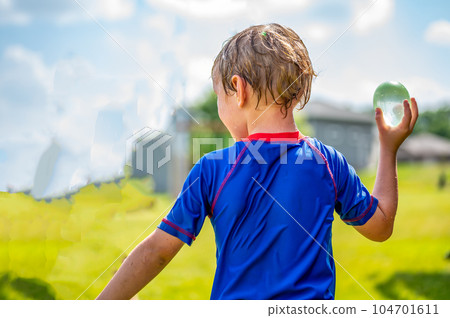 Young Caucasian boy taking aim to throw a water balloon. Young Caucasian boy taking aim to throw a water balloon. 104701611
