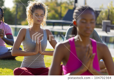 Group of diverse friends doing yoga and meditating in garden 104702364