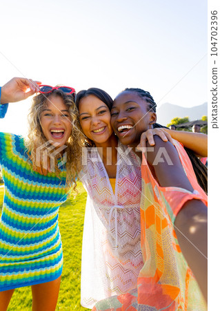 Happy diverse group of friends having party, taking a selfie in garden 104702396