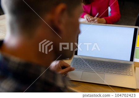 Laptop with copy space on screen and caucasian colleagues working at desk in casual office 104702423