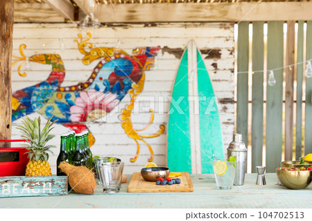 Countertop with fruit, cocktail shaker, glasses, bottles at sunny beach bar 104702513