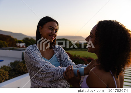 Biracial lesbian couple embracing in garden at sunset 104702674