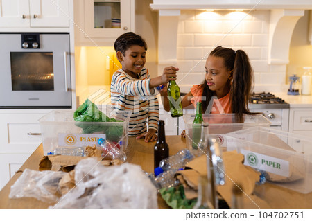 Happy biracial brother and sister sorting rubbish for recycling in kitchen Happy biracial brother and sister sorting rubbish for recycling in kitchen 104702751