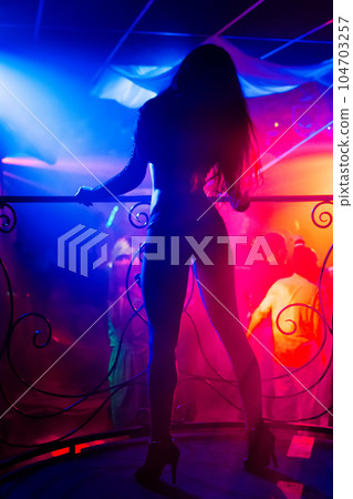 silhouette of slender girl dancing go-go on stage night club 104703257