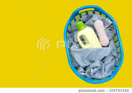 Jeans in laundry basket on yellow background. 104703388