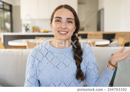 Portrait of happy caucasian woman having video call gesturing and wearing blue jumper at home Portrait of happy caucasian woman having video call gesturing and wearing blue jumper at home 104703392