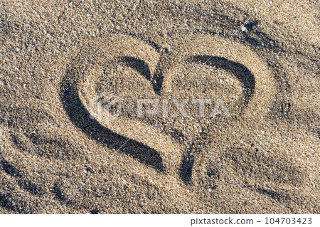 Drawing heart shape love concept on sand at the beach with vacation holiday summer travel background. Heart shape and footprint on sand. 104703423