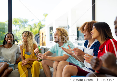 Group of happy diverse friends sitting on sofa, watching sport on tv 104703497