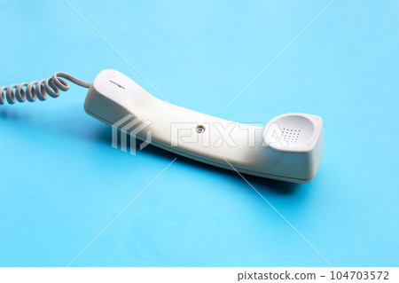 Handset of landline phone on blue background. 104703572