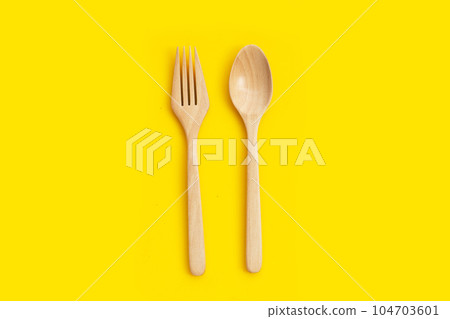 Wooden spoon and fork on yellow background. Wooden spoon and fork on yellow background. 104703601