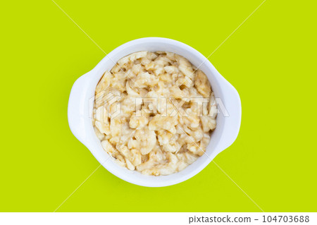 Mashed bananas in bowl on green background. 104703688