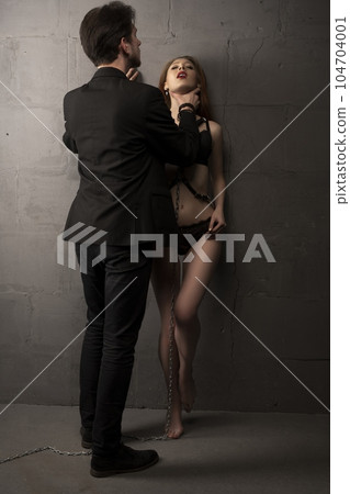 Stylish couple embracing in dark room with closed eyes 104704001