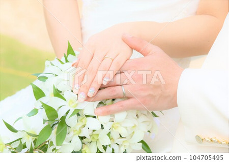 Bride and groom's hands with bouquet and wedding rings 104705495