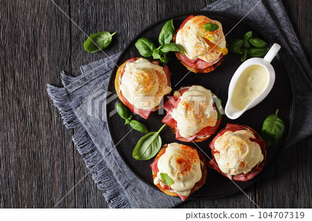 Eggs Benedict on black plate, top view 104707319