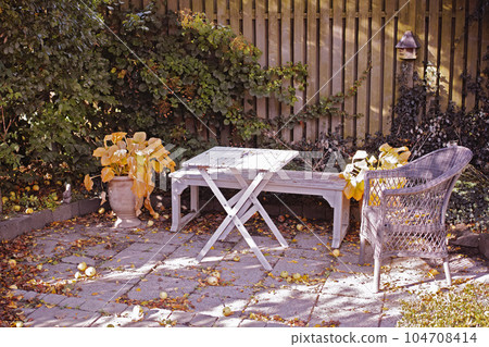 Cozy garden area for coffee and reading. Old wooden and forgotten furniture in a stone patio outdoors with copy space. Private location to relax and enjoy alone time in warm summer weather outside 104708414