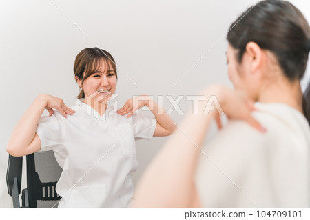 Female doctor, physiotherapist, nurse and patient receiving stretching and gymnastics rehabilitation guidance at a chiropractic clinic / osteopathic clinic with stiff shoulders 104709101