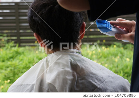 man getting a haircut in the garden man getting a haircut in the garden 104709896