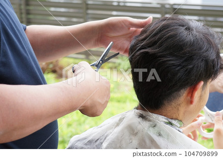 Son getting a haircut from his father Son getting a haircut from his father 104709899