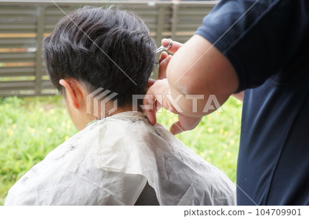 man getting a haircut in the garden man getting a haircut in the garden 104709901