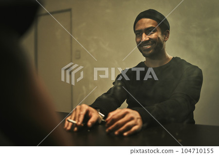 Man, suspect smoking and detective in interrogation room with criminal, terrorist or interview with a gangster. Police officer, murder questioning and statement on crime and person with cigarette 104710155