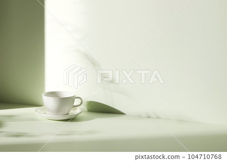 A room with various objects such as warm sunlight, shadows of grass leaves, a vase on a table, and cups 104710768