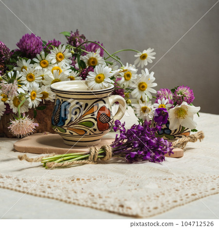 A cup of coffee and spring wildflowers on a white tablecloth. A cup of coffee and spring wildflowers on a white tablecloth. 104712526