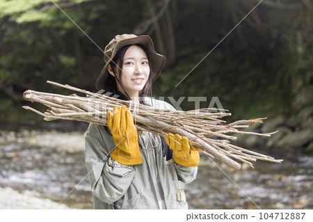Young woman picking up branches for bonfire at campsite Young woman picking up branches for bonfire at campsite 104712887