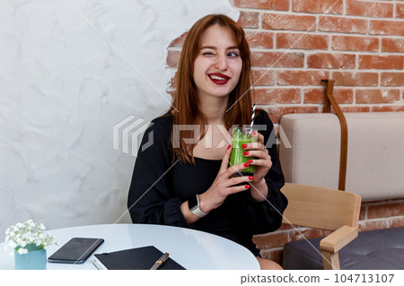 The girl in the cafe shows a funny face. The girl in the cafe shows a funny face. 104713107