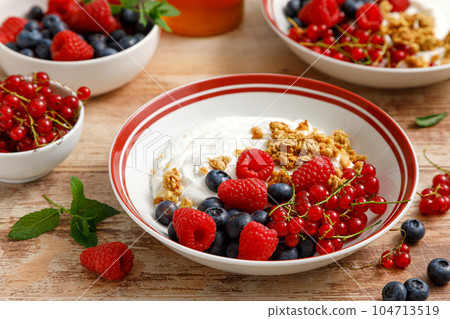 Yogurt with berries on wooden background. White plain greek yogurt with fresh berries and granola, top view. Healthy food, breakfast menu 104713519