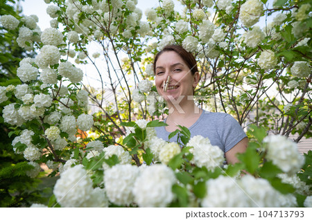 Happy woman with a clothespin on her nose on a walk in a blooming park.  104713793