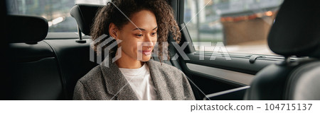 Cheerful businesswoman accountant working on laptop sitting car backseat on the way to office Cheerful businesswoman accountant working on laptop sitting car backseat on the way to office 104715137