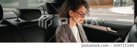 Executive woman manager working on laptop sitting car leather backseat on the way to office Executive woman manager working on laptop sitting car leather backseat on the way to office 104715140